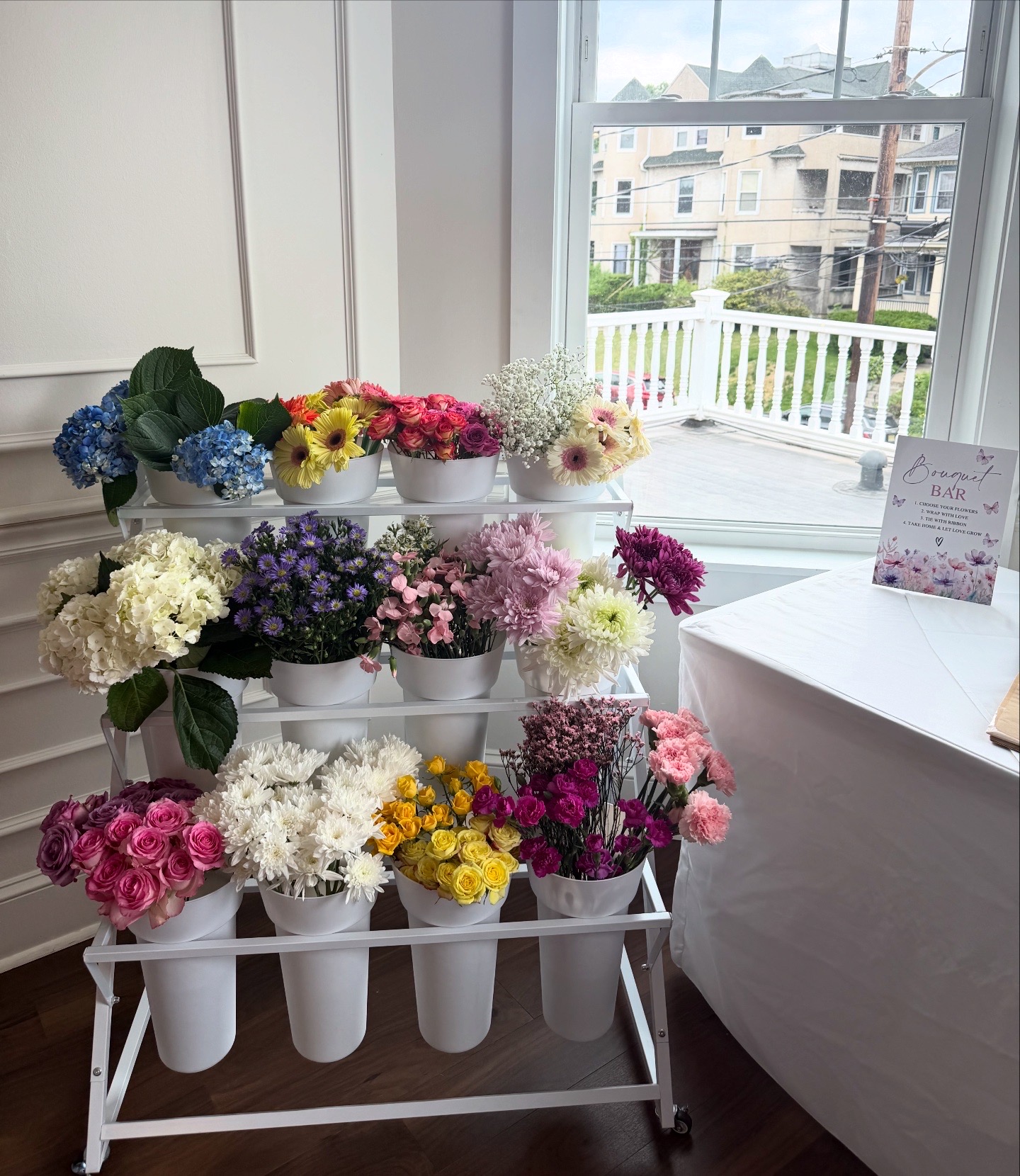 Bloom bar flower stand with fresh roses, hydrangeas and daisies by a window at a Bergen County, NJ venue